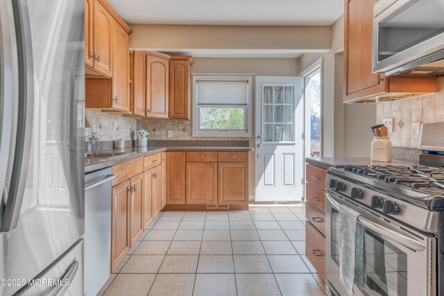 kitchen featuring backsplash, dark countertops, visible vents, light tile patterned flooring, and appliances with stainless steel finishes