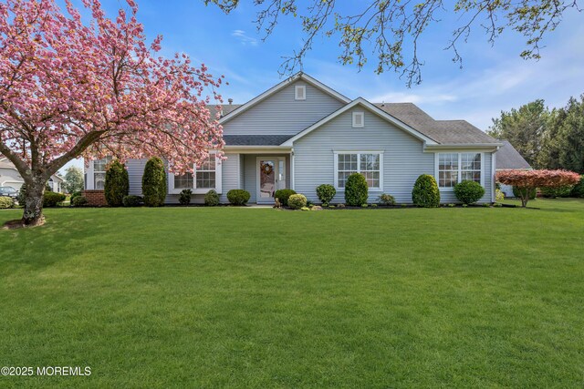 ranch-style home with roof with shingles and a front yard