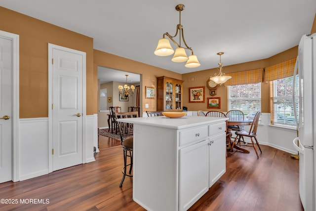 kitchen with white cabinetry, dark wood-style floors, freestanding refrigerator, a notable chandelier, and hanging light fixtures