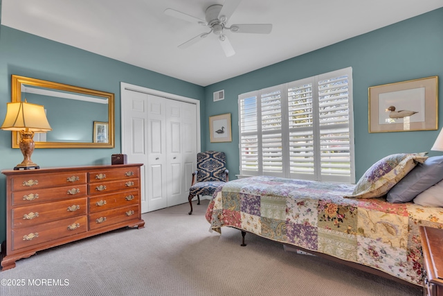 carpeted bedroom with a closet, visible vents, and a ceiling fan