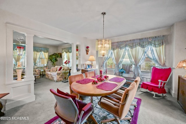 carpeted dining space with ornate columns, an inviting chandelier, and a healthy amount of sunlight