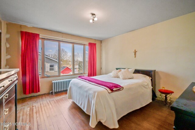 bedroom featuring radiator heating unit and wood-type flooring