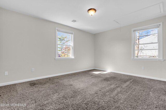unfurnished room featuring a wealth of natural light, attic access, carpet, and baseboards