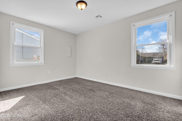 empty room featuring a healthy amount of sunlight, carpet flooring, baseboards, and visible vents