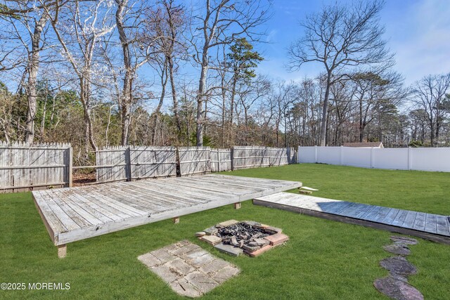 view of yard with a deck, a fenced backyard, and an outdoor fire pit