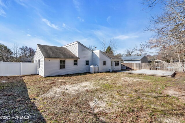 rear view of property featuring a yard, roof with shingles, and a fenced backyard