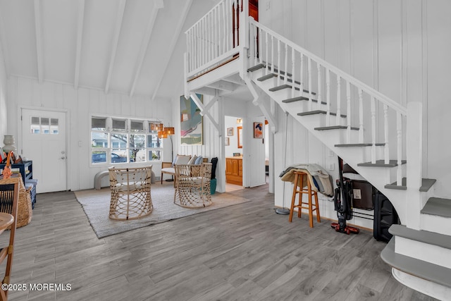 living area featuring beamed ceiling, wood finished floors, high vaulted ceiling, and stairway