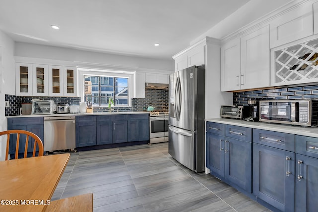 kitchen with stainless steel appliances, white cabinetry, decorative backsplash, light countertops, and under cabinet range hood