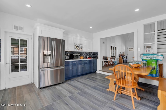kitchen with white cabinets, decorative backsplash, blue cabinetry, appliances with stainless steel finishes, and visible vents