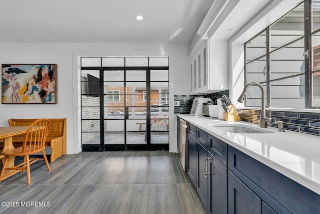kitchen with recessed lighting, light countertops, stainless steel dishwasher, a sink, and decorative backsplash