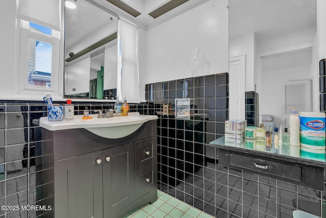 bathroom featuring vanity, wainscoting, tile patterned flooring, and tile walls