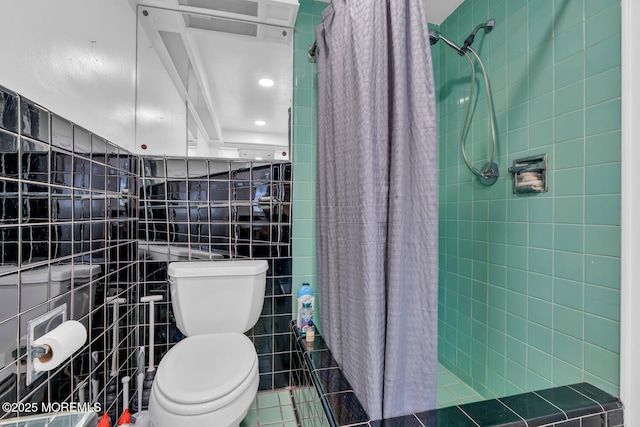 full bathroom with tiled shower, toilet, tile patterned flooring, and tile walls