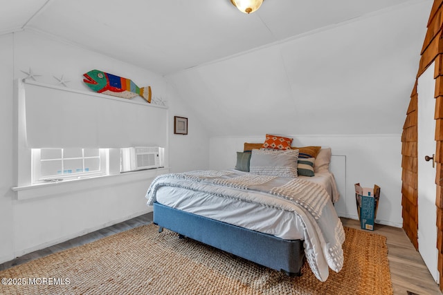 bedroom with vaulted ceiling and wood finished floors