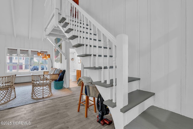 staircase with wood finished floors, beam ceiling, and a decorative wall