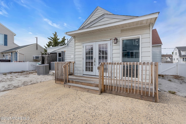view of front facade featuring a wooden deck, french doors, central AC unit, and fence