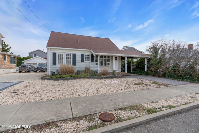 cape cod-style house with driveway, a porch, and a shingled roof