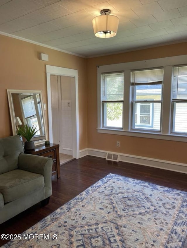 living area featuring crown molding, baseboards, a wealth of natural light, and hardwood / wood-style flooring