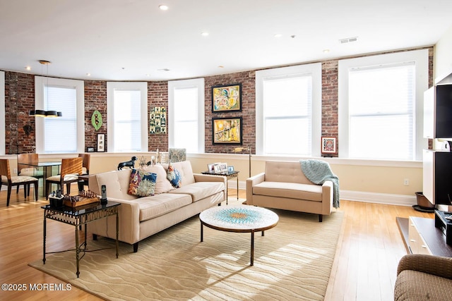 living room with recessed lighting, baseboards, light wood-type flooring, and brick wall