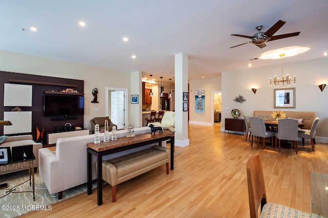 living room featuring light wood-style floors, ceiling fan with notable chandelier, baseboards, and recessed lighting