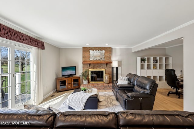living room with wood finished floors, baseboards, ornamental molding, and a brick fireplace