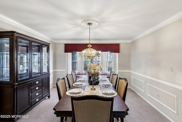 carpeted dining space featuring ornamental molding, a wainscoted wall, and a notable chandelier