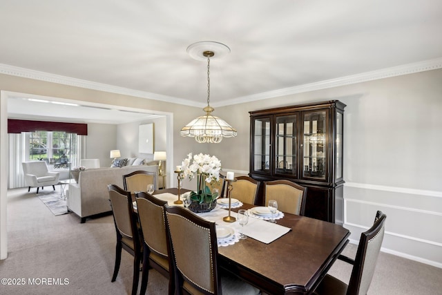 dining room with a chandelier, baseboards, light colored carpet, and crown molding