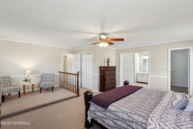 carpeted bedroom featuring a closet, baseboards, ceiling fan, crown molding, and ensuite bath