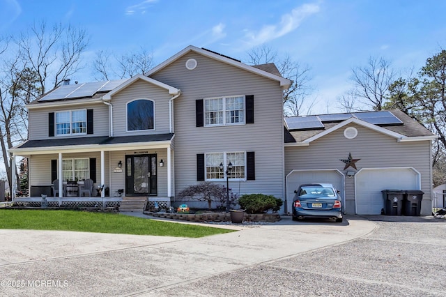 view of front of property featuring a front yard, roof mounted solar panels, an attached garage, covered porch, and driveway