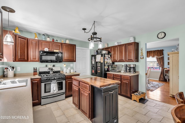 kitchen featuring a sink, wooden counters, black appliances, pendant lighting, and a kitchen island