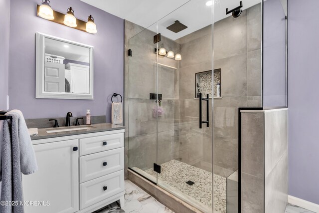 full bath with vanity, marble finish floor, and a stall shower