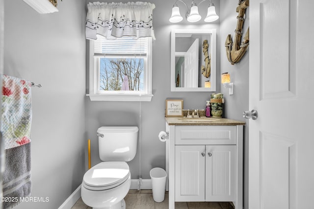 half bathroom featuring toilet, vanity, baseboards, and tile patterned flooring