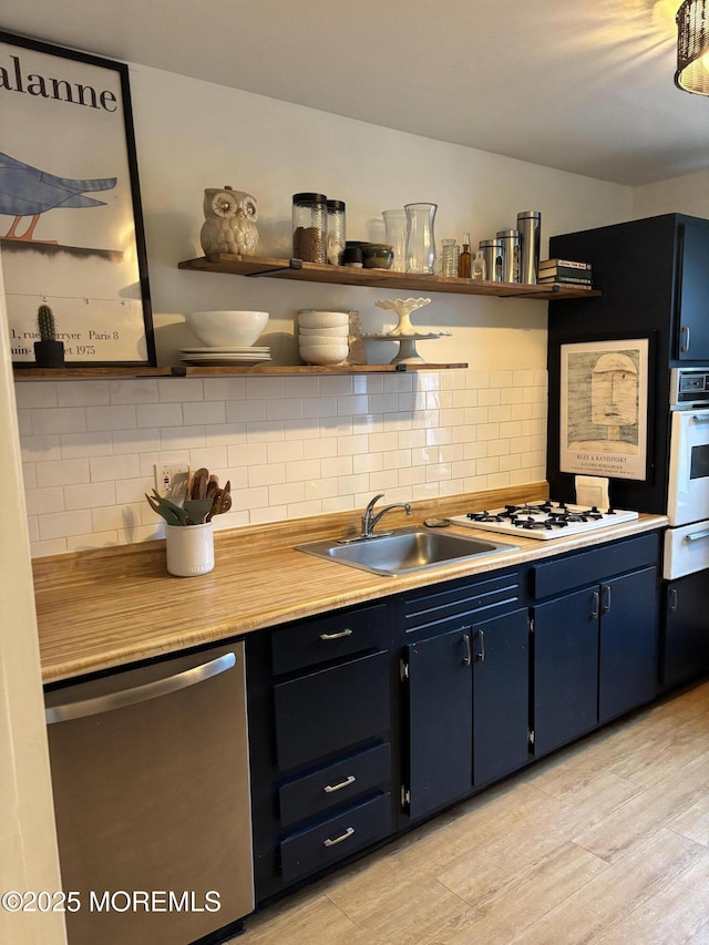 kitchen with white appliances, open shelves, blue cabinets, a sink, and decorative backsplash