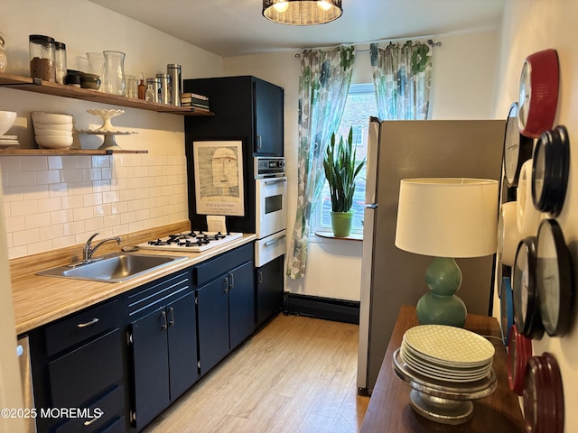 kitchen with open shelves, a sink, white appliances, light wood finished floors, and decorative backsplash