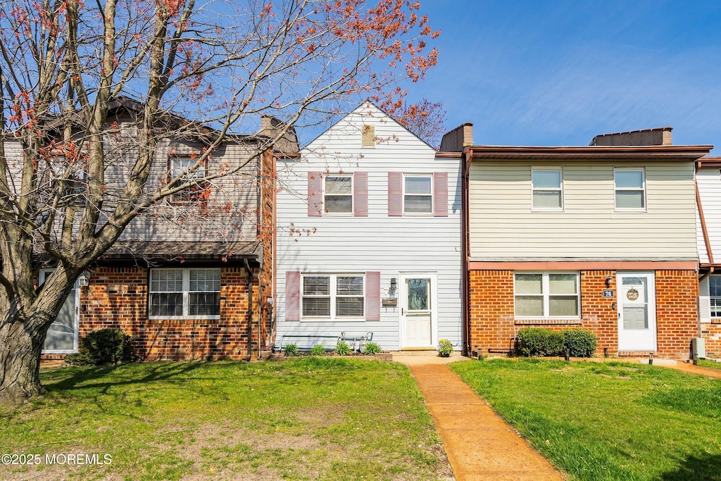 townhome / multi-family property with brick siding and a front lawn