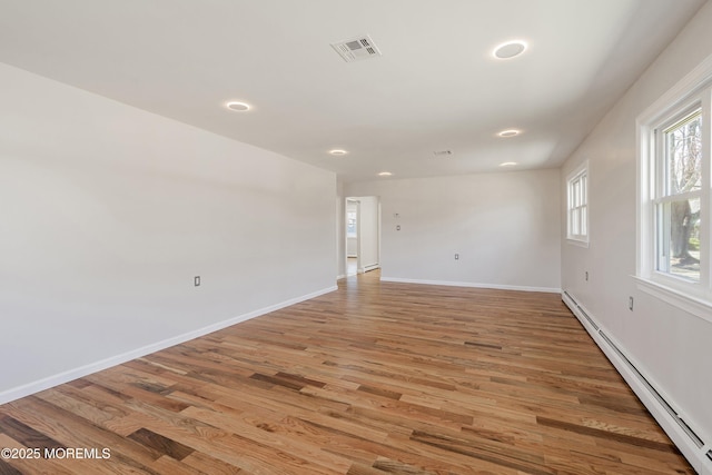 empty room featuring baseboard heating, light wood-style floors, baseboards, and recessed lighting