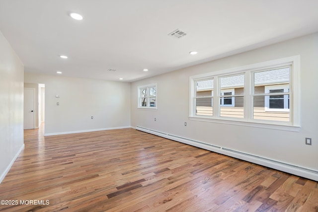 empty room featuring baseboard heating, baseboards, recessed lighting, light wood-style flooring, and visible vents