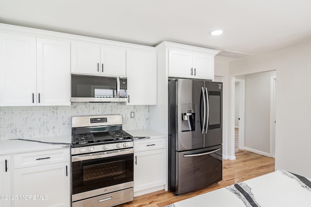 kitchen with light countertops, white cabinetry, decorative backsplash, stainless steel appliances, and light wood finished floors