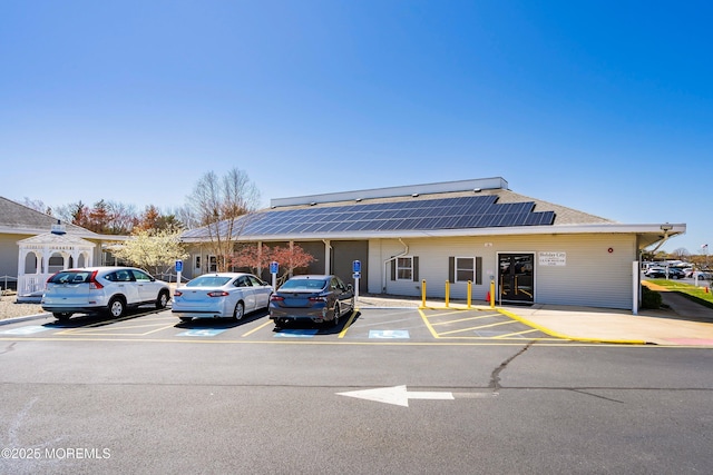 exterior space with roof with shingles, uncovered parking, and roof mounted solar panels
