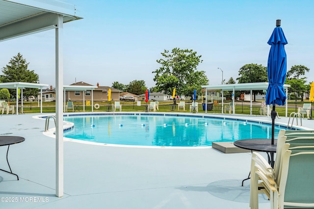 community pool with a patio area and fence