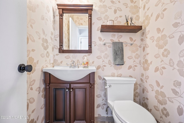 bathroom featuring wallpapered walls, toilet, and vanity