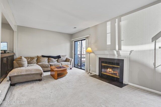 living room featuring visible vents, baseboards, carpet flooring, and a fireplace with flush hearth
