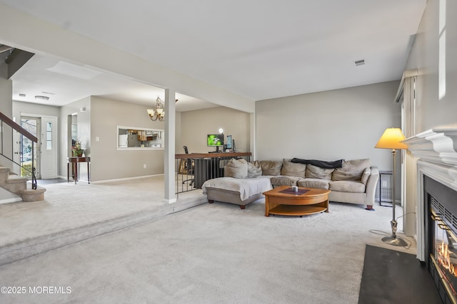 living room with a glass covered fireplace, visible vents, light carpet, stairs, and a notable chandelier