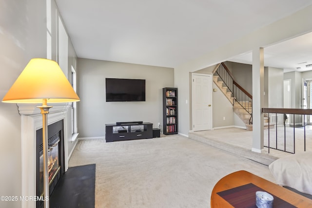 living area featuring carpet floors, baseboards, stairway, and a glass covered fireplace