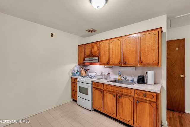 4 Flamingo Ter Unit A, Manchester, NJ 08759 - kitchen with white range with gas cooktop, under cabinet range hood, brown cabinets, and light countertops