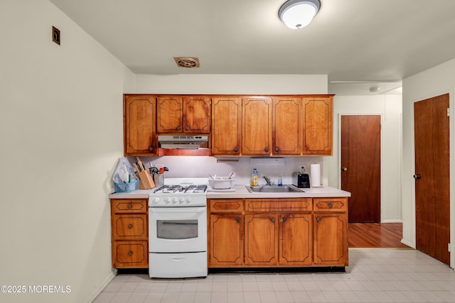 4 Flamingo Ter Unit A, Manchester, NJ 08759 - kitchen featuring white range with gas cooktop, under cabinet range hood, brown cabinetry, light countertops, and light flooring