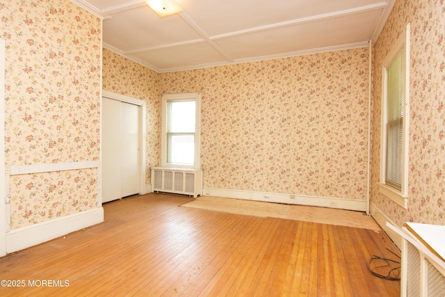unfurnished room with crown molding, baseboards, radiator heating unit, and hardwood / wood-style flooring
