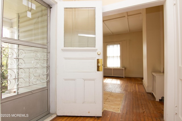 doorway with baseboards, radiator heating unit, and hardwood / wood-style flooring