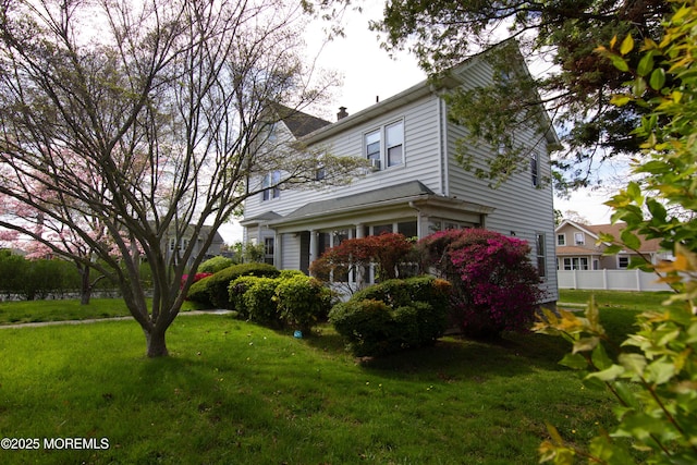back of house featuring a lawn, fence, and a chimney