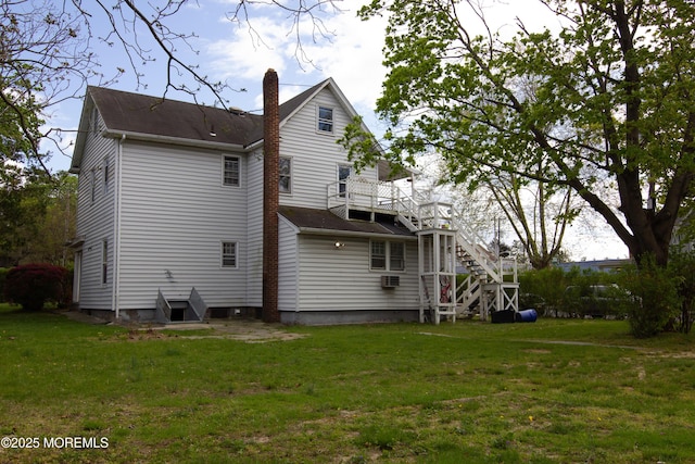 back of property featuring a yard, a deck, a chimney, and stairs