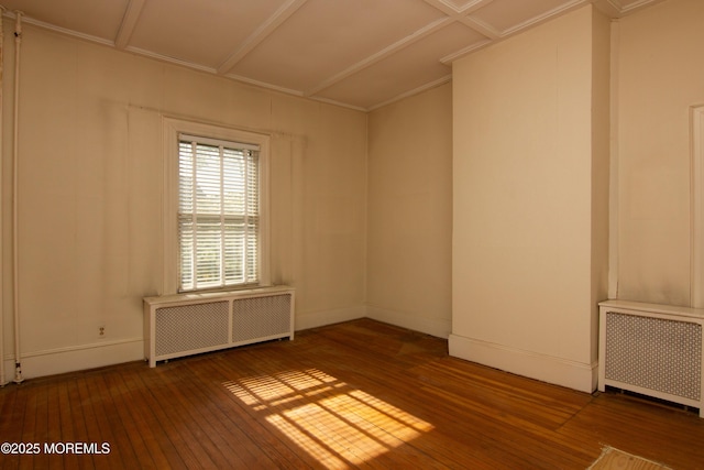 empty room featuring baseboards, radiator, and hardwood / wood-style flooring